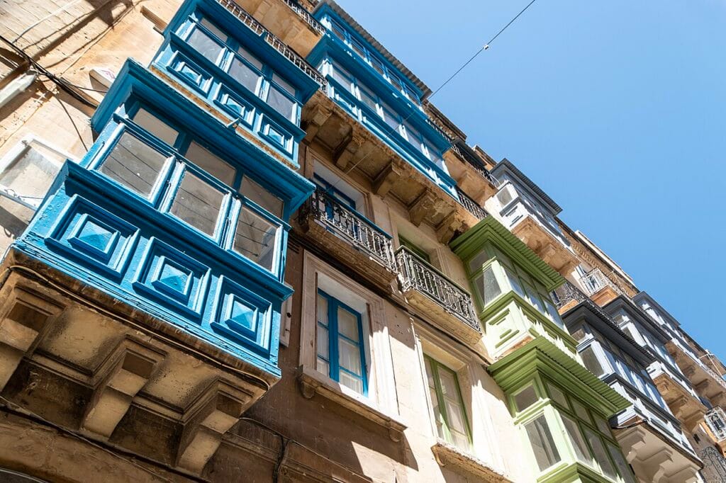 Traditional Maltese gallariji — colourful enclosed wooden balconies on limestone facades